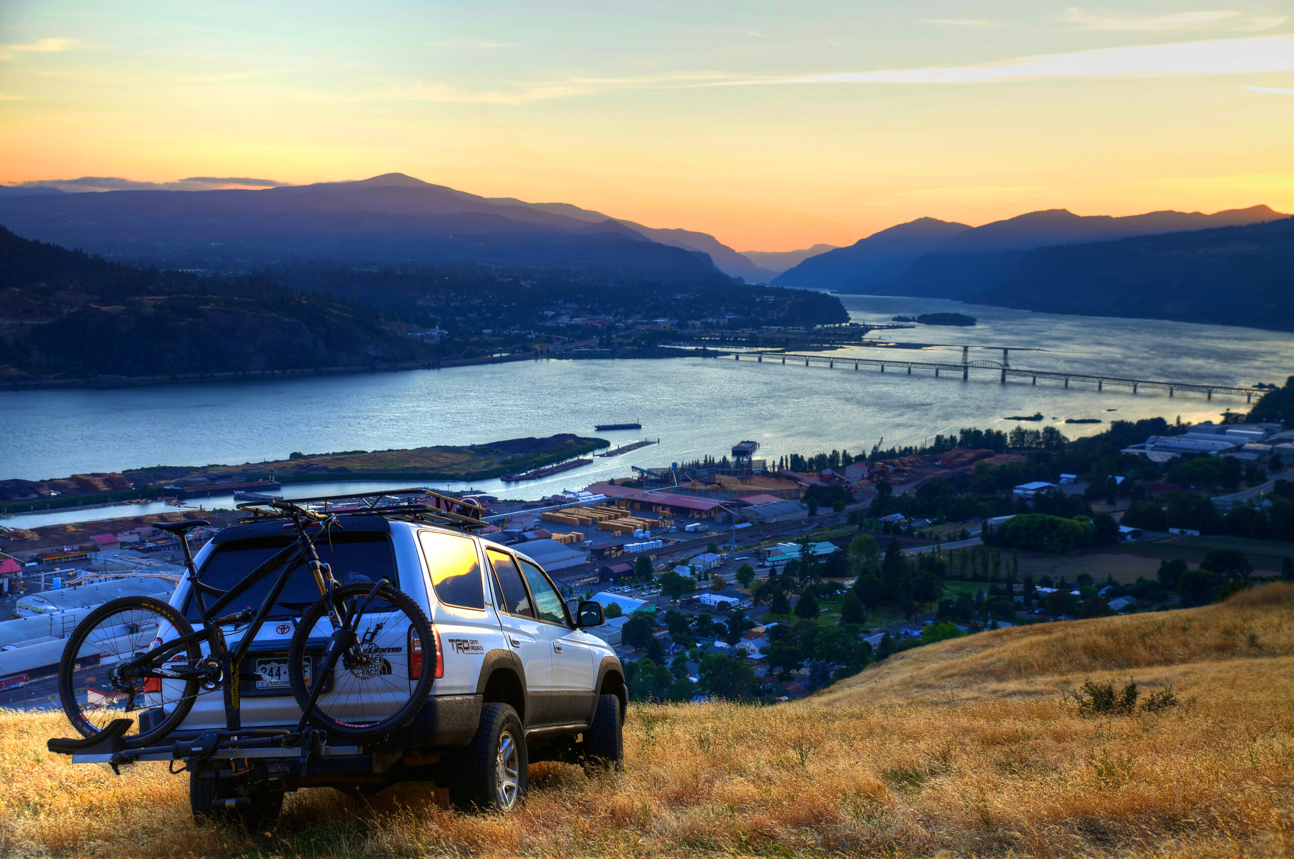 SUV with mountain bikes parked above the Columbia River Gorge at sunset in Hood River, Oregon