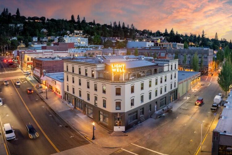 Historic Lightwell Hotel in downtown Hood River at sunset with rooftop sign and panoramic city view.