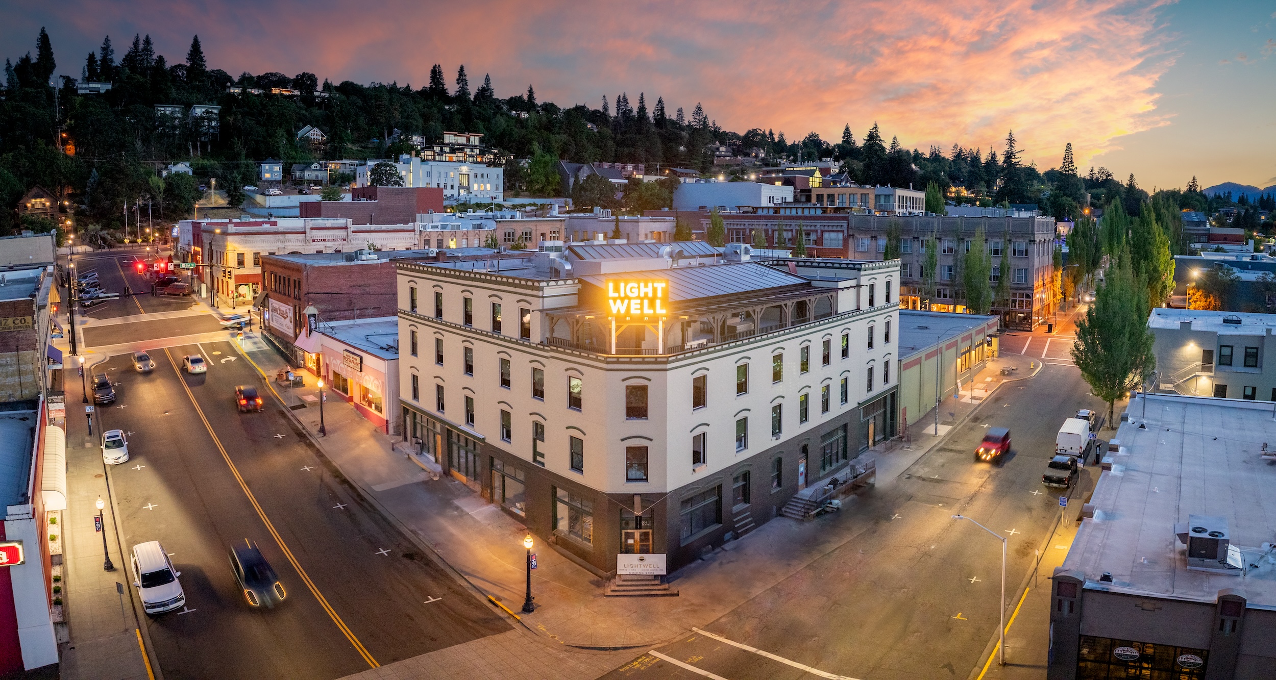 Historic Lightwell Hotel in downtown Hood River at sunset with rooftop sign and panoramic city view.