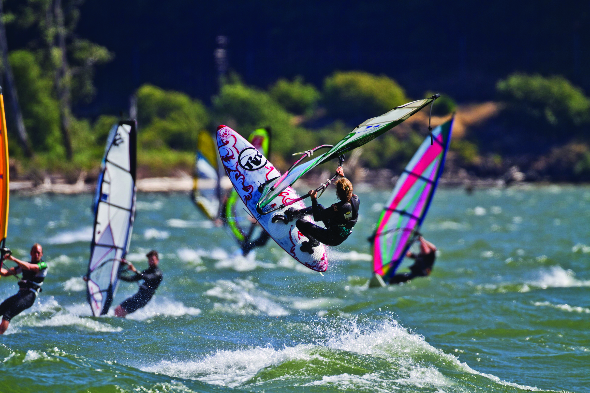 Group of windsurfers riding waves on the Columbia River Gorge in Hood River, Oregon on a sunny day.