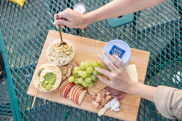 Charcuterie board with fruit, dips, crackers, and cheese served on the patio at Lightwell Hotel's Basecamp market.