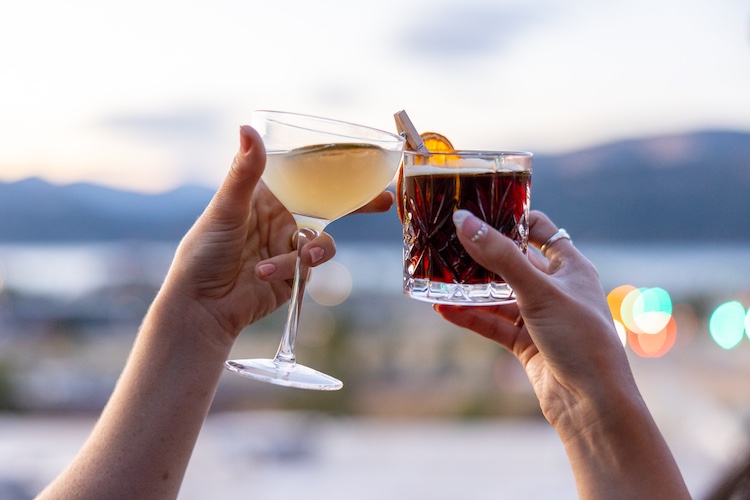 Two guests clinking cocktails at Lightwell Hotel’s rooftop bar in Hood River with Columbia River Gorge views at sunset.