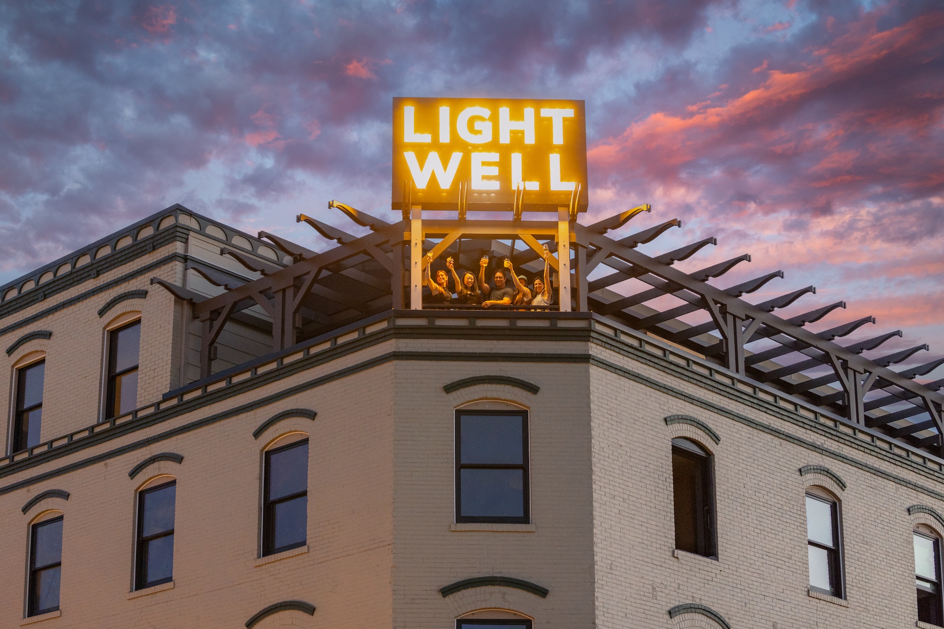 Guests raising glasses at Lightwell Hotel’s rooftop bar at sunset in Hood River, Oregon.