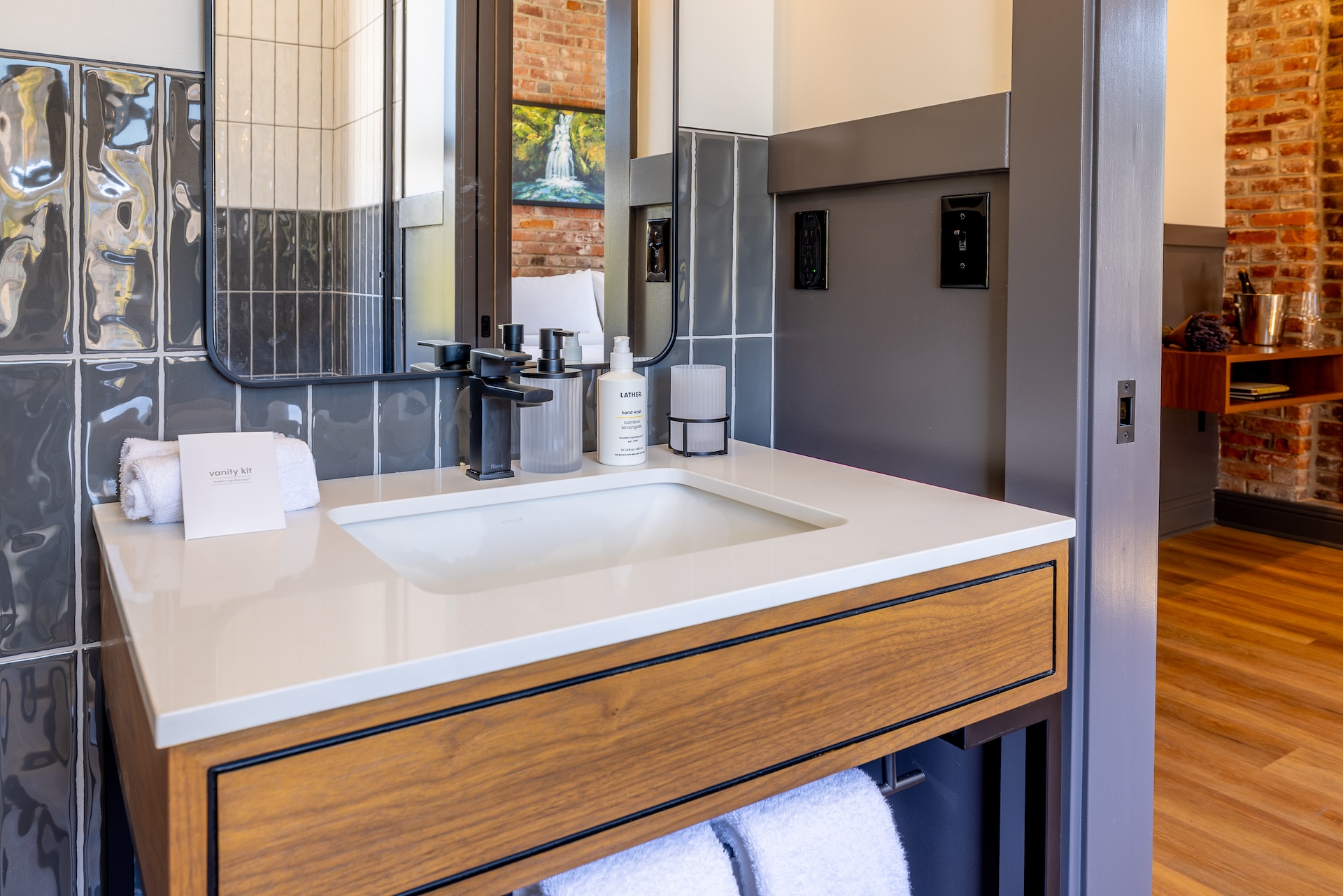 City View King guest room bathroom vanity at Lightwell Hotel & Spa in Hood River with modern sink, wood cabinetry, and designer tile backsplash.