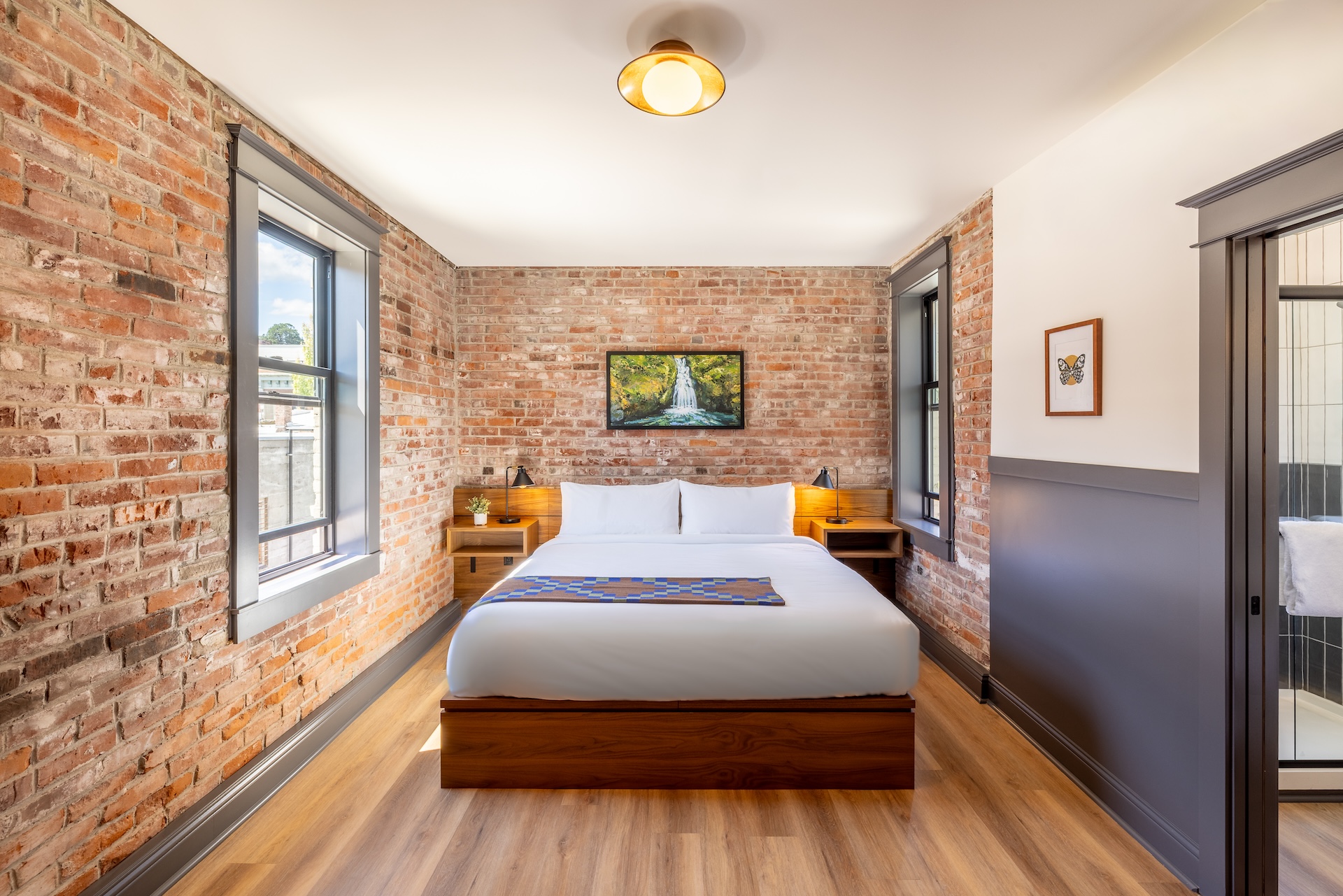 City View King room at Lightwell Hotel Hood River with exposed brick walls, king bed, and large window.