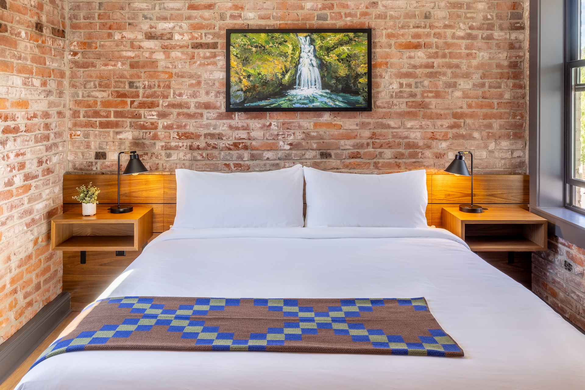 City View King guest room at Lightwell Hotel & Spa in Hood River featuring a king bed with white linens, exposed brick wall, and modern wood nightstands.