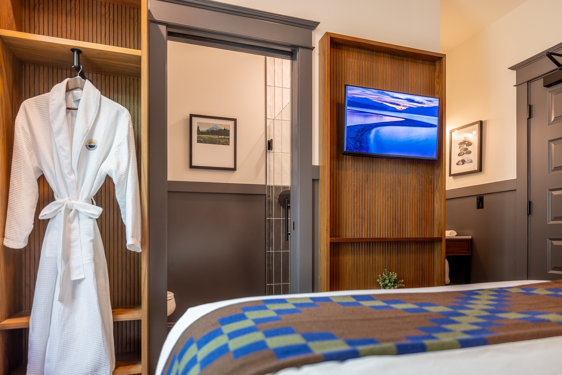 Lightwell Hotel & Spa Queen guest room amenities in Hood River with plush robe, wall-mounted TV, modern wood finishes, and ensuite bathroom.