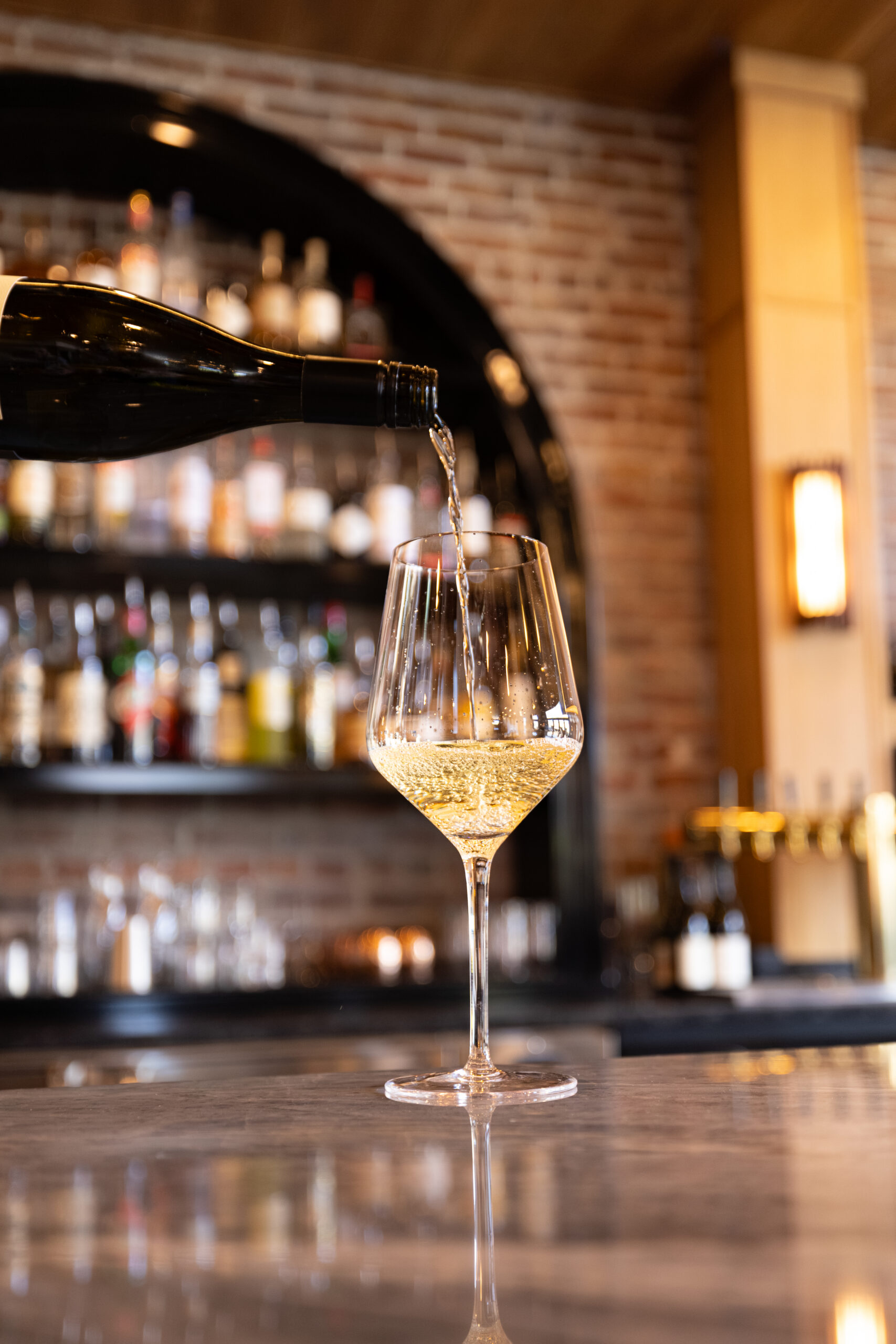 Glass of white wine being poured at the bar inside Lightwell Hotel in Hood River, Oregon.