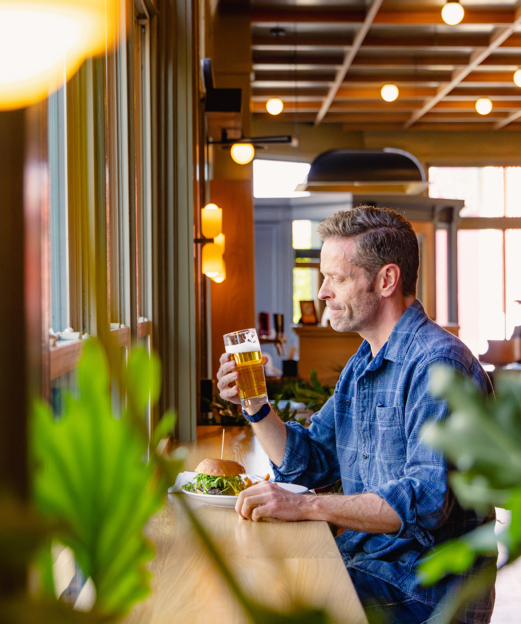 Man enjoying a beer and a burger at the lobby bar inside Lightwell Hotel